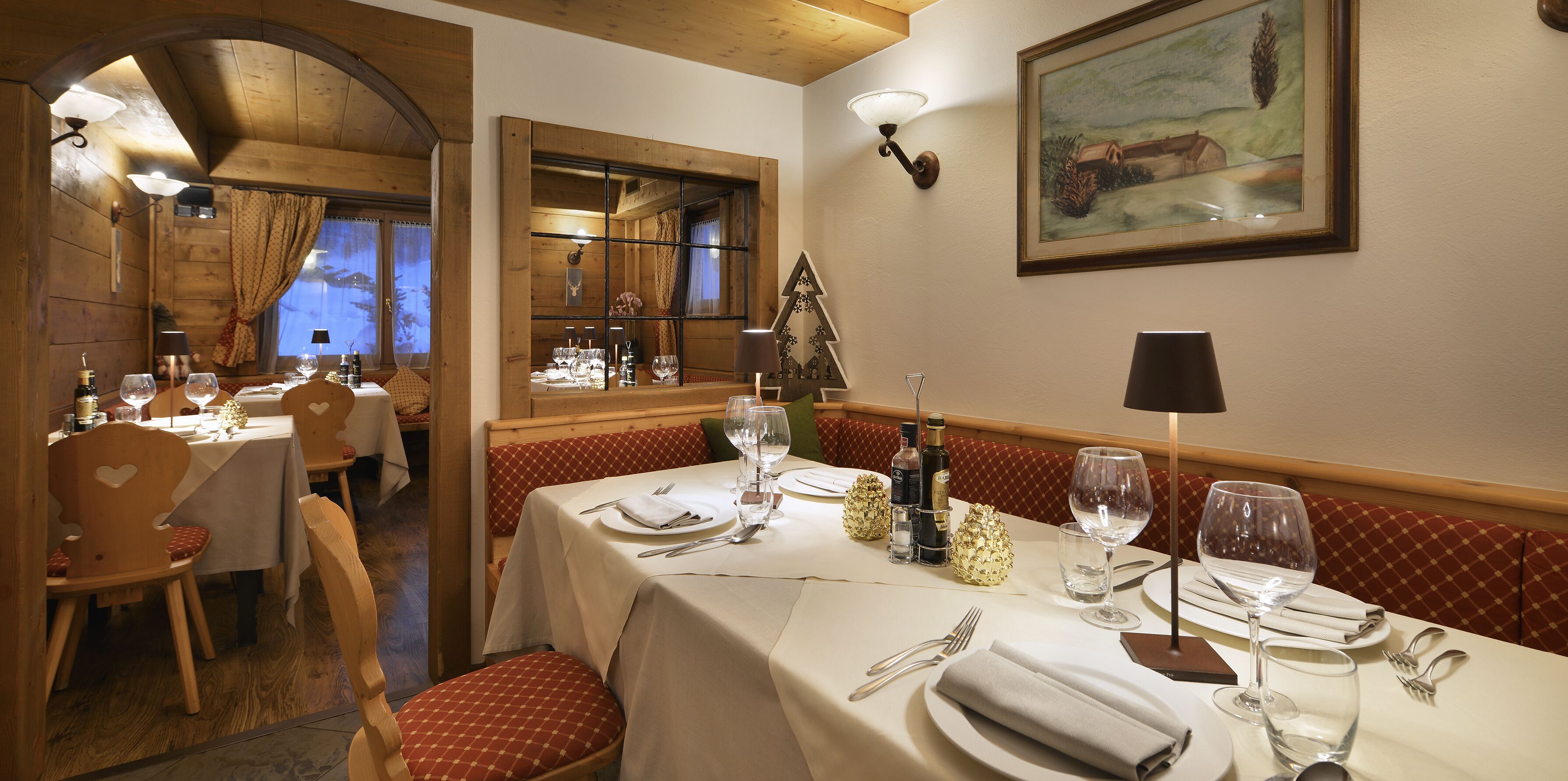 A dining area with wooden furniture, white tablecloths, and neatly set tables with wine glasses and cutlery.
