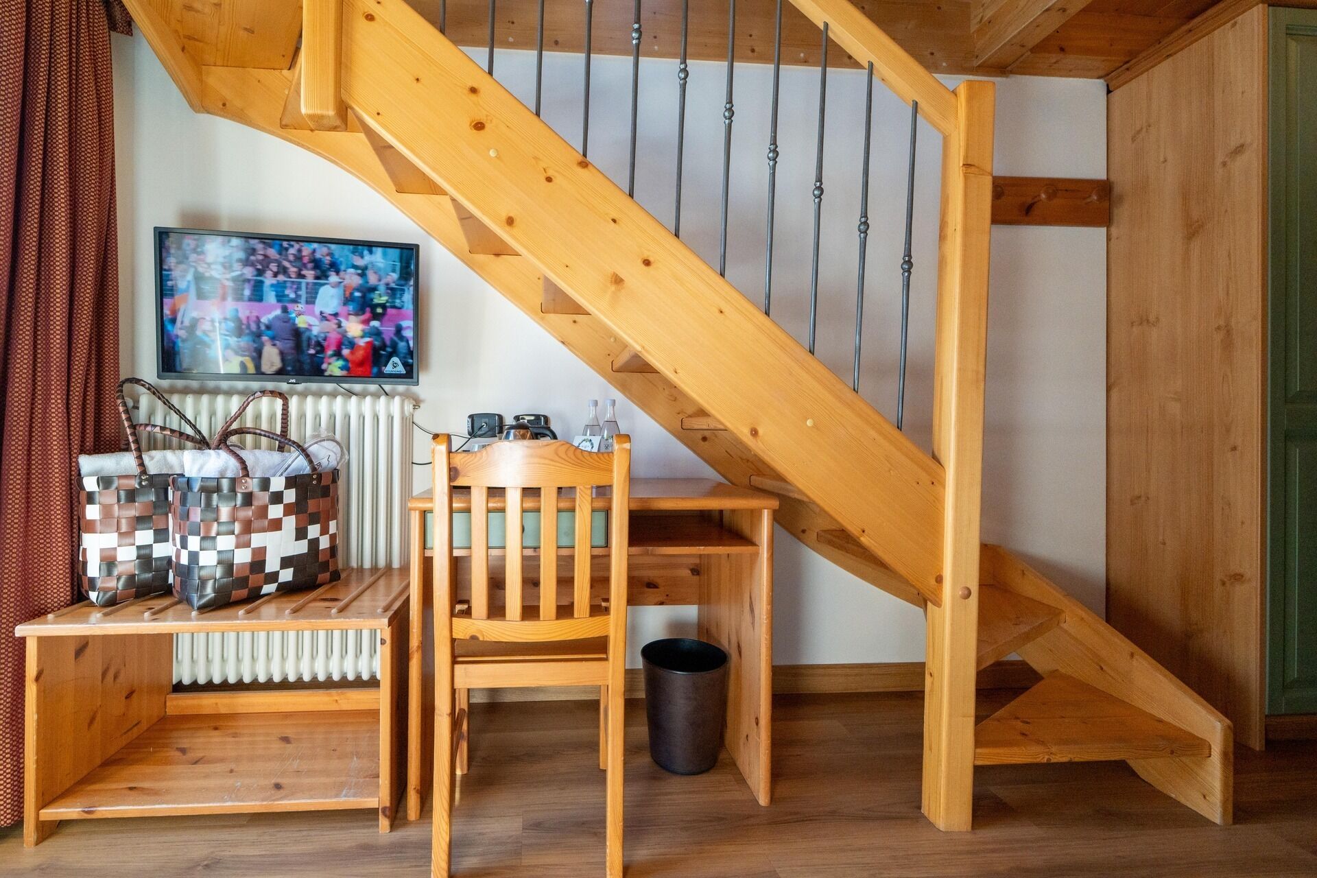 A wooden staircase with a television mounted on the wall above it.
