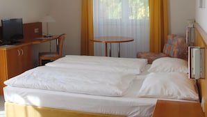 A hotel room with a bed, a desk with a computer, a chair, and a small table. - Business Hotel Siebeneichen GmbH (Meissen)