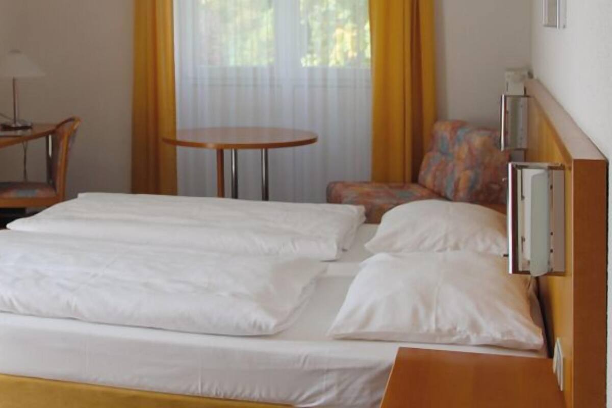 Une chambre d’hôtel avec un lit, un bureau avec un ordinateur, une chaise et une petite table.