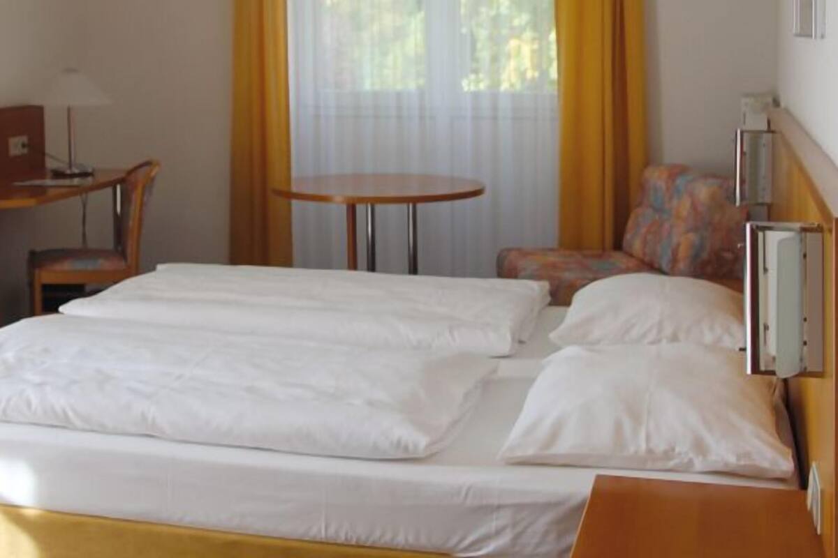Une chambre d’hôtel comprenant un lit, un bureau avec un ordinateur, une chaise, une petite table et un téléviseur.