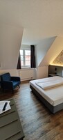 Una habitación con cama, escritorio, silla, ventana con cortinas y radiador.