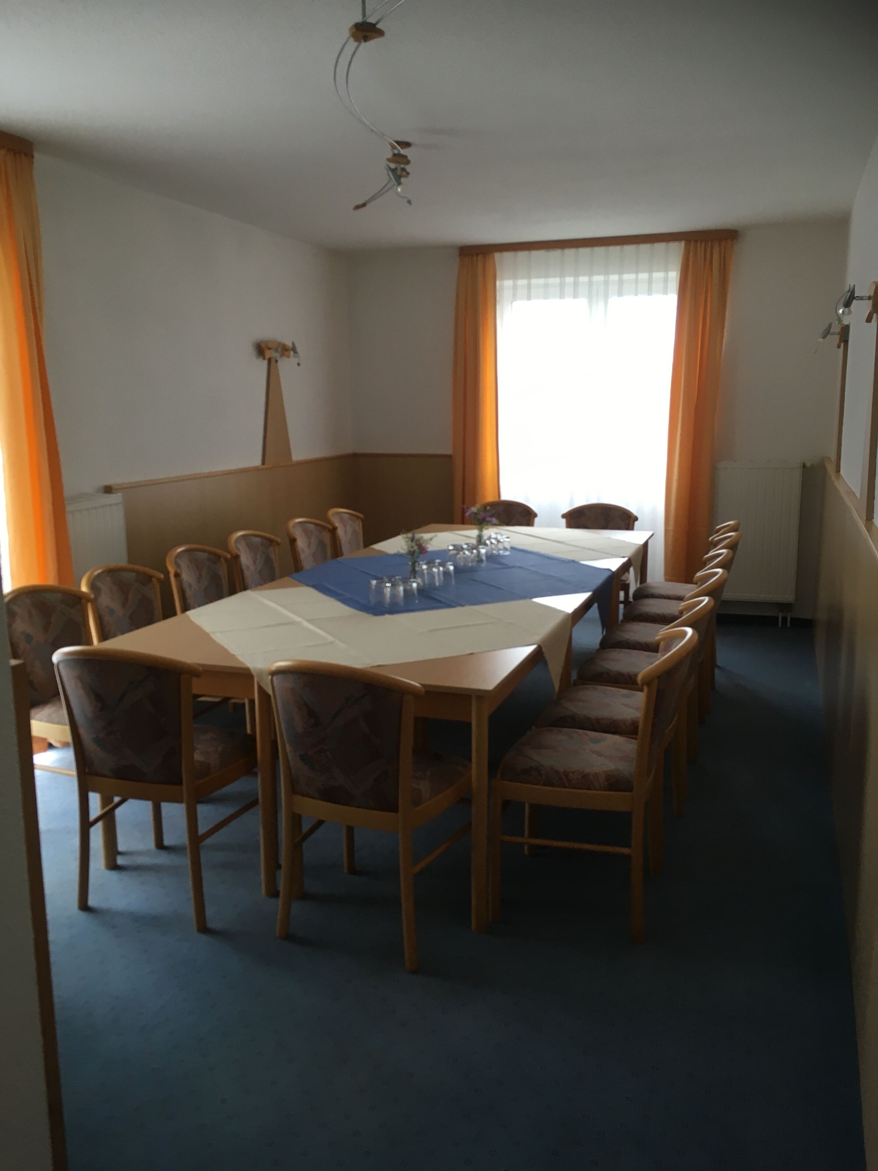 Ein Konferenzraum mit langem Tisch, Stühlen und Deckenventilator.
