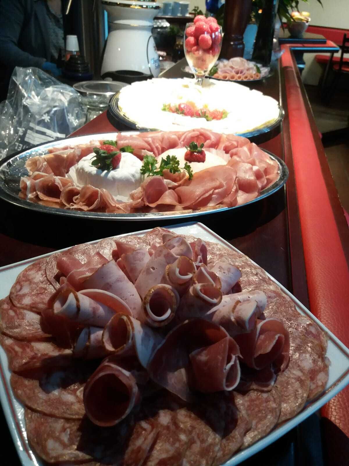 A table with various food items, including sliced meats and a dessert with berries.