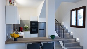 Eine moderne Küche mit weißen Schränken, einer Holz Arbeitsplatte und einem eingebauten Backofen. Zwei schwarze Stühle stehen an der Arbeitsplatte.