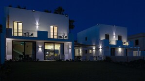 Ein modernes, zweistöckiges Haus mit Balkon, einer überdachten Terrasse und einer sichtbaren Treppe, die zum oberen Stockwerk führt.