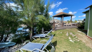Un patio con sillones de descanso, un pabellón y vistas a un cuerpo de agua.