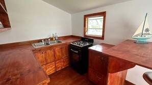 Una cocina compacta con armarios de madera, una estufa a gas y un ventanal con vistas.