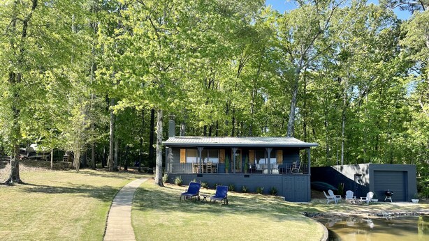 A lakeside cabin with a deck, outdoor seating, and a small dock. - The Cozy Cabin on Lake Martin (Eclectic)