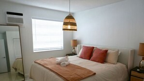Un dormitorio con cama, lámparas de noche, un espejo y una ventana.
