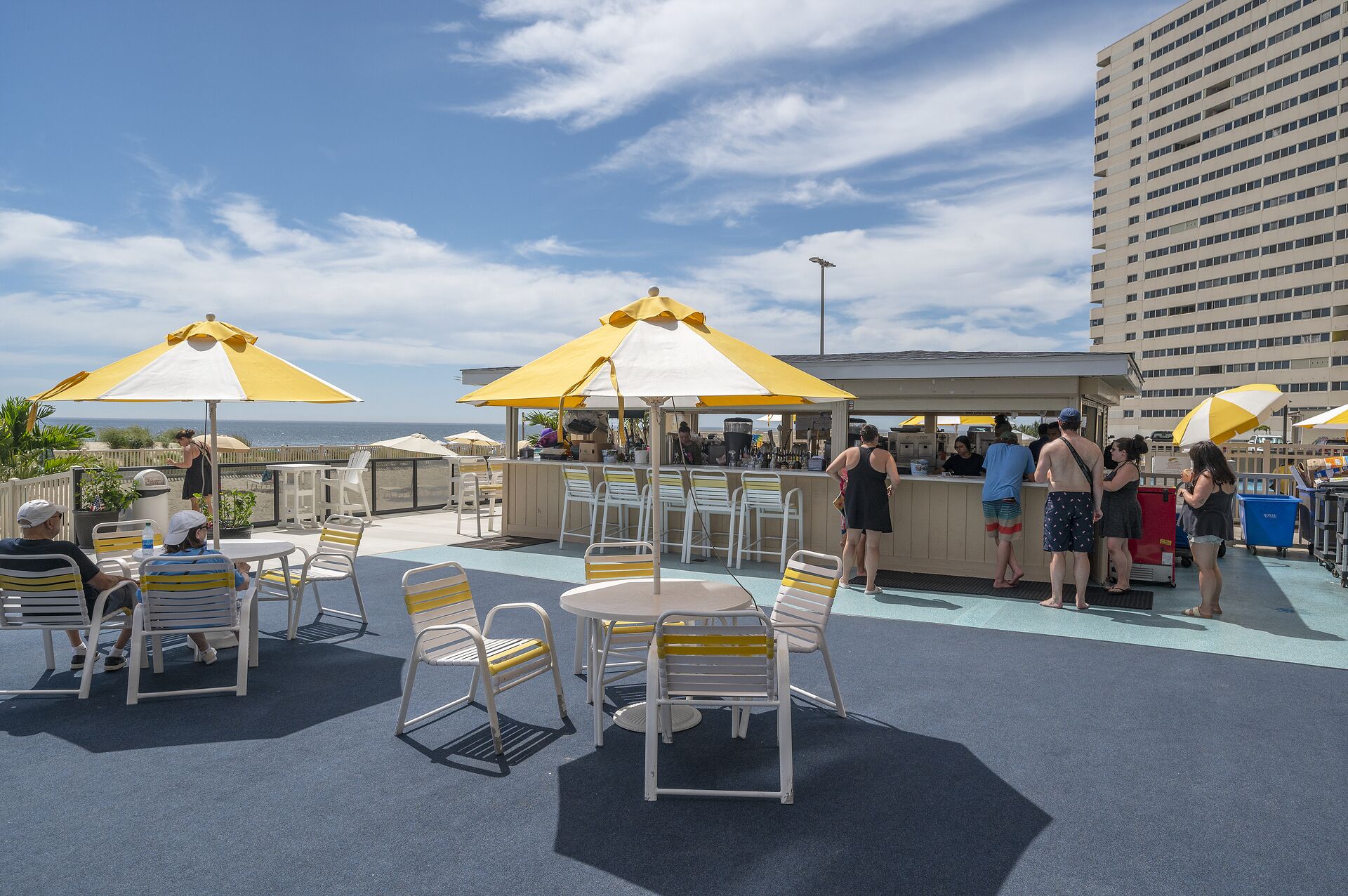 A rooftop bar with yellow umbrellas, outdoor seating, and a view of the ocean.