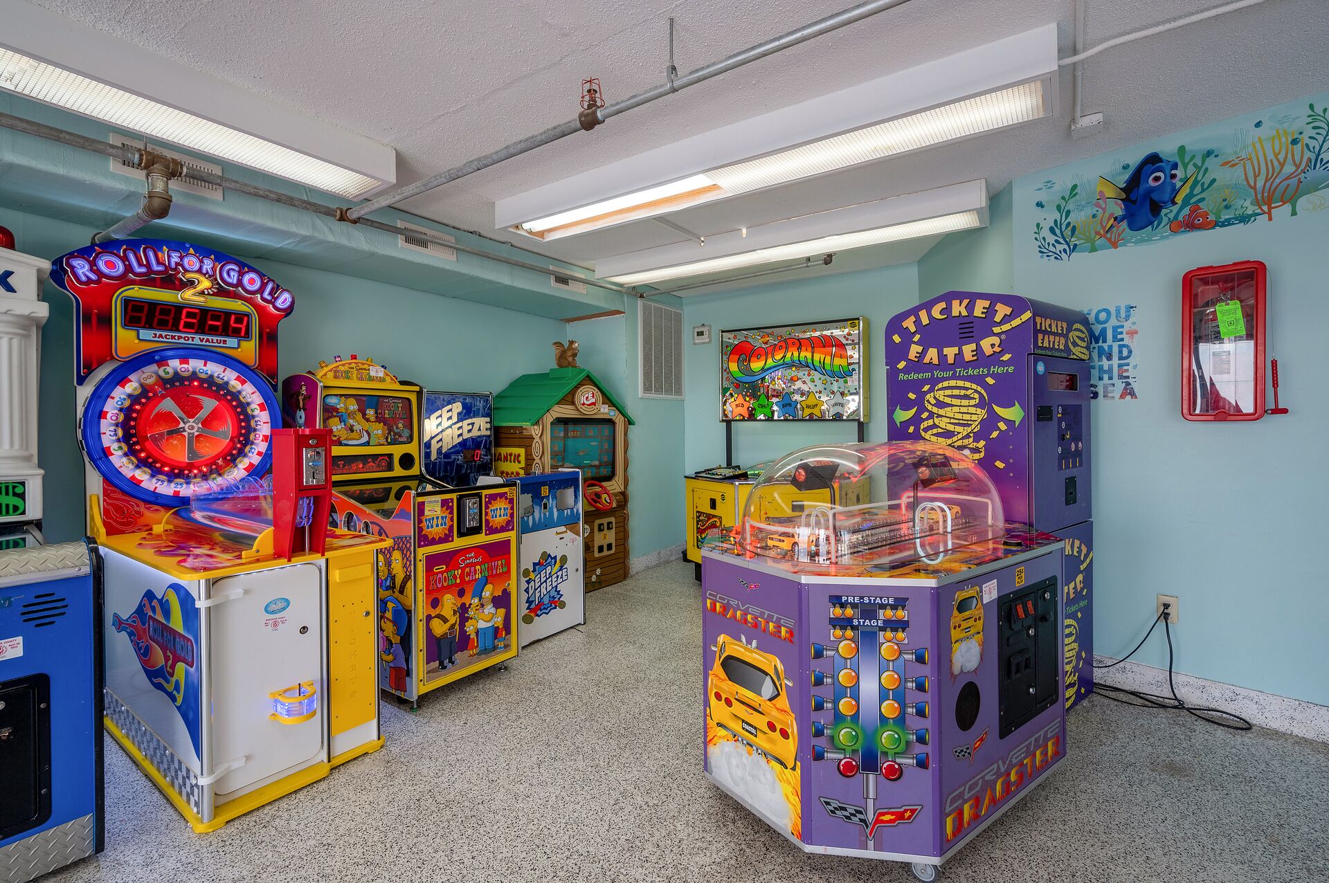 Une salle remplie de différents jeux d’arcade, notamment un appareil à jackpot intitulé « Roll for Gold » et un jeu appelé « Ticket Eater ».