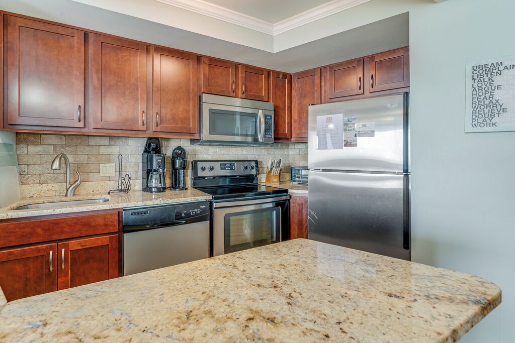 A kitchen with wooden cabinets, stainless steel appliances, granite countertops, and a dishwasher.