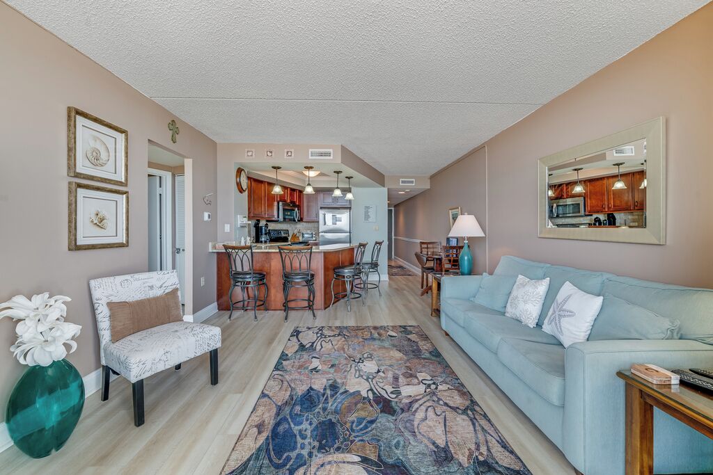 A living room with a sofa, a coffee table, a rug, and a dining area with chairs and a table.