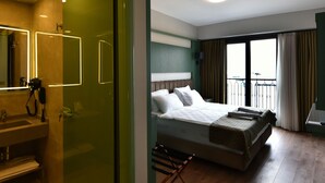A hotel room with a bed, a bathroom with a mirror, and a balcony with curtains. - ASPEN HOTEL ÇANAKKALE (Çanakkale)