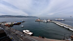 A harbor with boats, a pier, and a cityscape in the background. - ASPEN HOTEL ÇANAKKALE (Çanakkale)