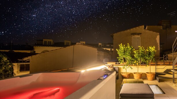 Eine Dachterrasse mit Pool, Topfpflanzen und einem klaren Nachthimmel.