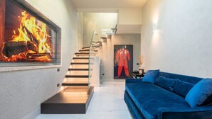 Ein modernes Interieur mit Kamin, einem blauen Sofa und einer Treppe, die in einen anderen Raum führt.