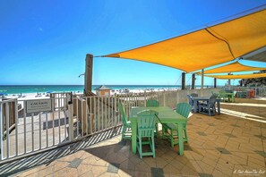 Eine Terrasse direkt am Strand mit Tisch und Stühlen, einem Warnschild und Blick auf den Ozean.