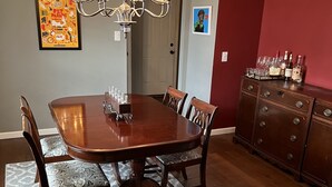 Une salle à manger avec une table en bois, des chaises, un lustre et un tapis.