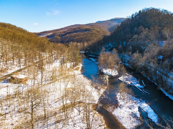 A river flowing through a forested valley with snow on the ground.