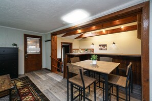 A dining area with a wooden table and chairs, a small potted plant, and a staircase leading to another room. - Riverside De Luxe*WiFi*Steps to the River (Elkins)