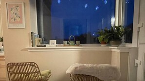 A room with a window sill, two wicker chairs, a white cushion, a potted plant, and a framed picture on the wall. - Peaceful Country Cottage (Kinghorn)
