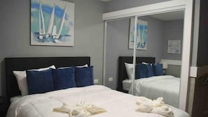 A hotel room with a large bed, a mirror, and a painting of sailboats on the wall. - Hotel Boutique Calizo vip Guest House # 4 (Fajardo)