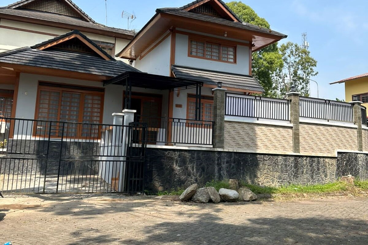 Et traditionelt japansk hus med tegltag, træbjælker og en stenvæg.