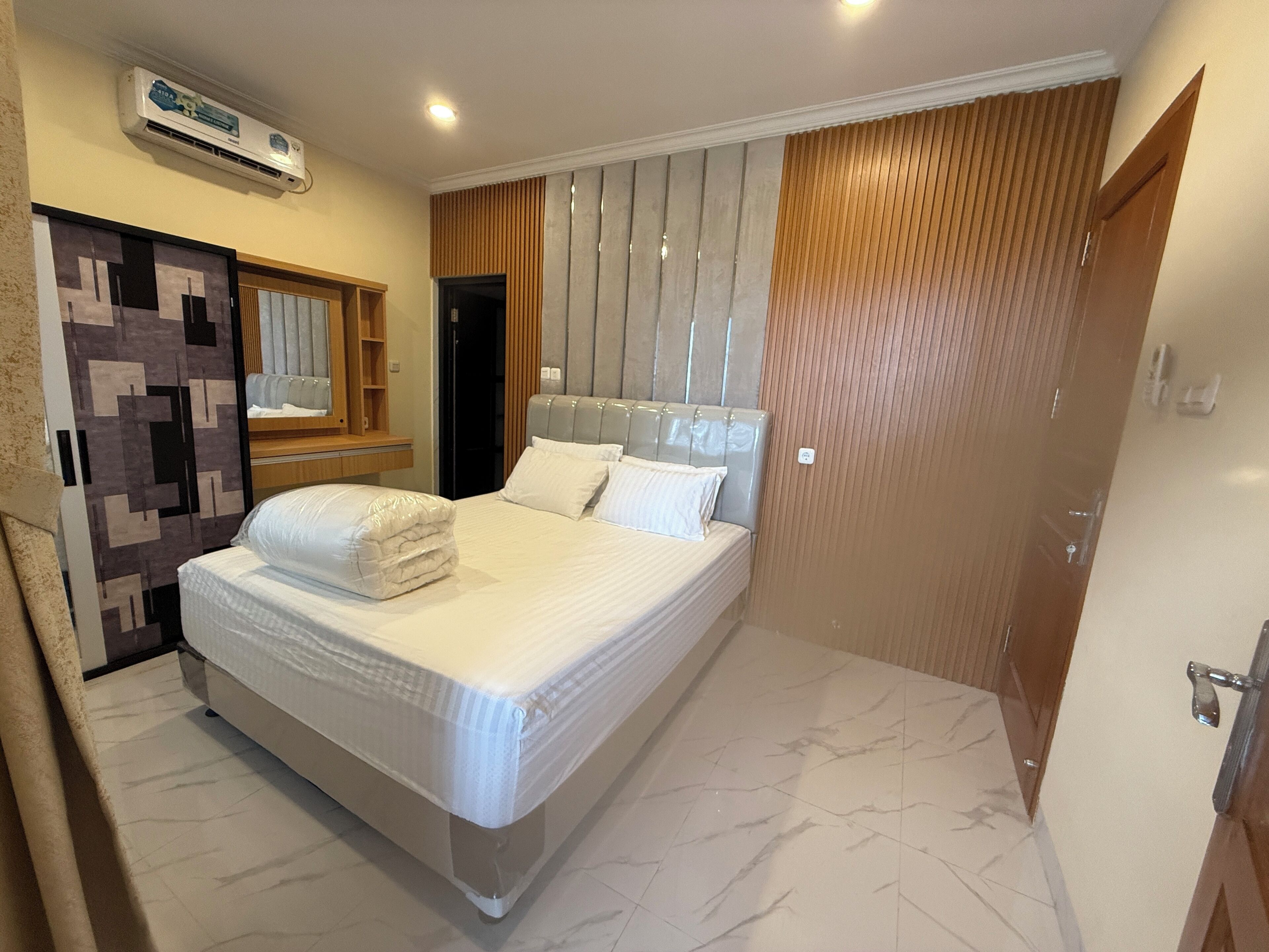 Ein modernes Hotelzimmer mit einem großen Bett, einem Kleiderschrank, einem Spiegel und einer Tür.