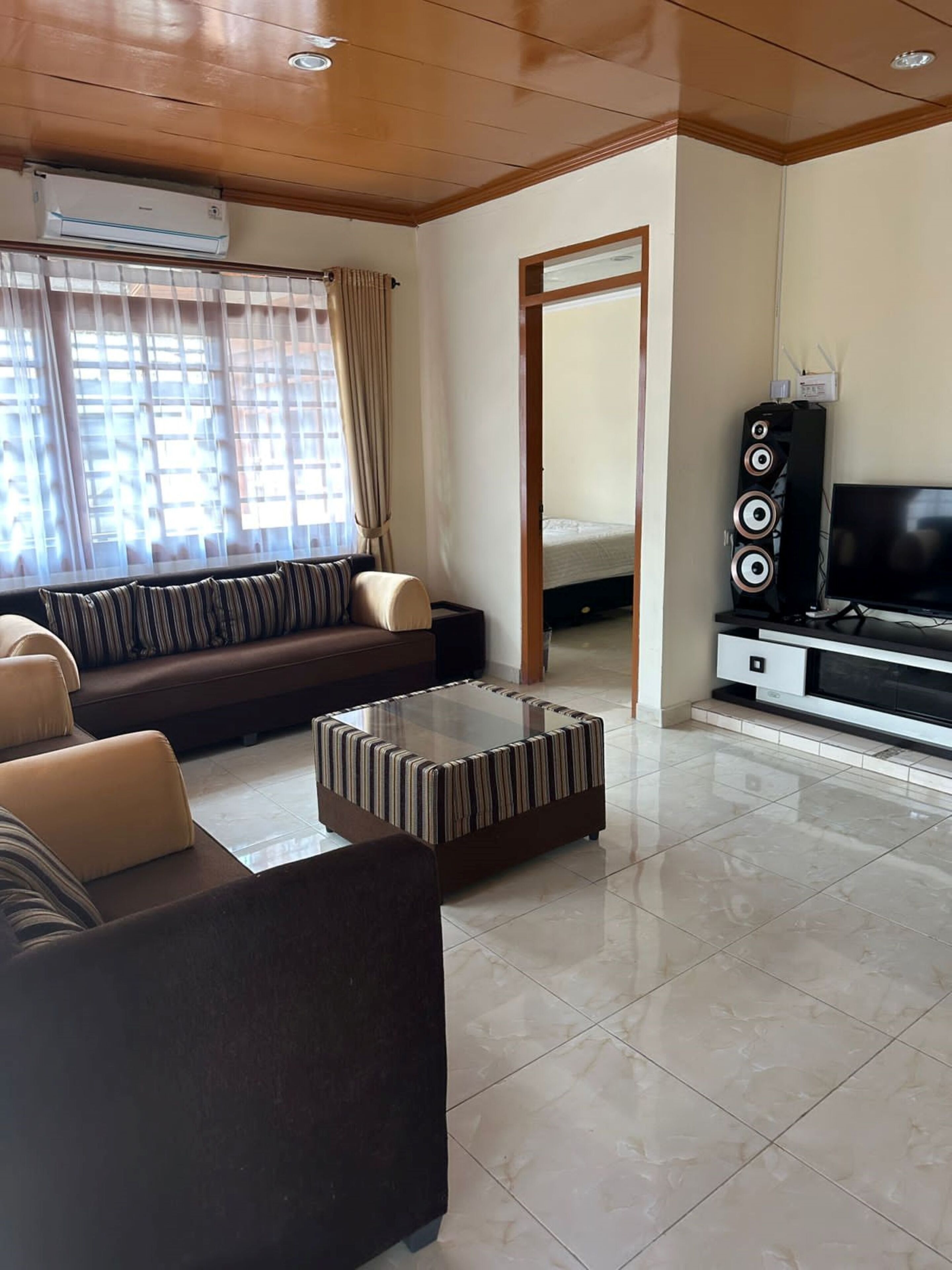 A modern living room with a sofa, ottoman, and entertainment unit.