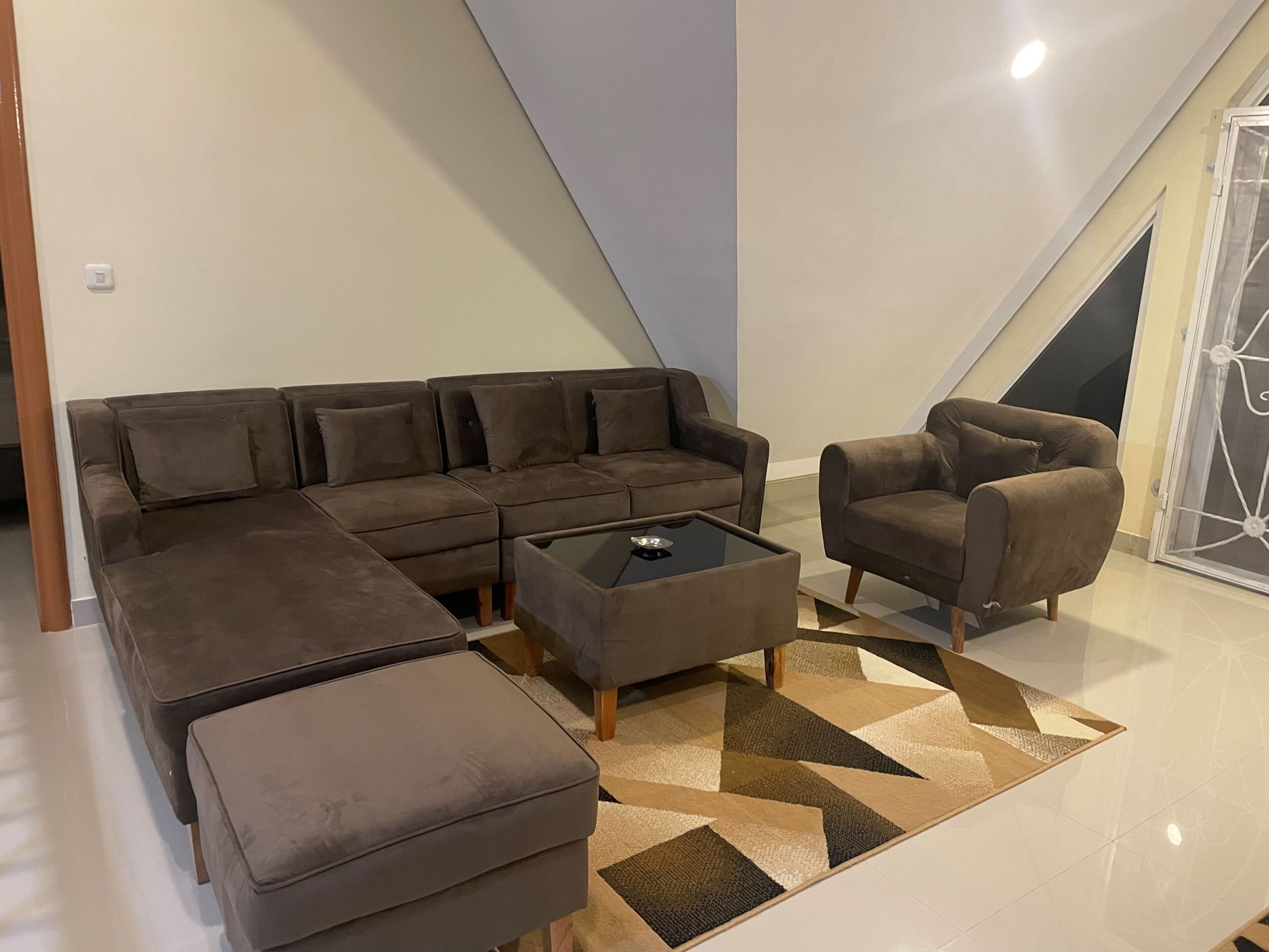Una sala moderna con un sofá seccional, un sillón individual y una mesa de centro.