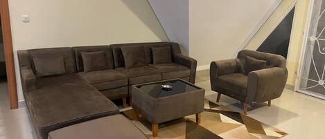 Una sala moderna con un sofá seccional, un sillón individual y una mesa de centro.