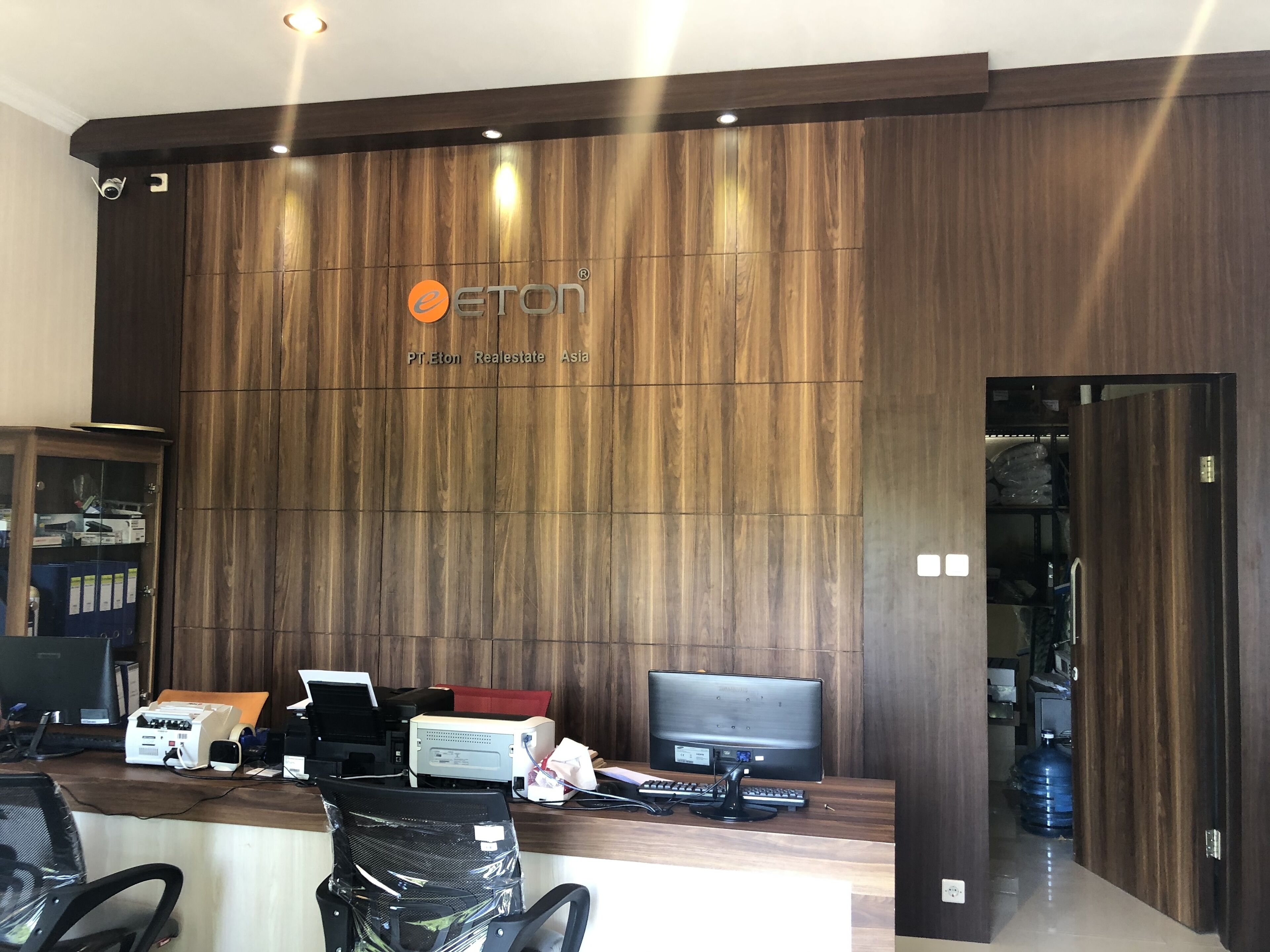 A reception desk with a wooden backdrop, a Samsung monitor, a printer, and a computer.