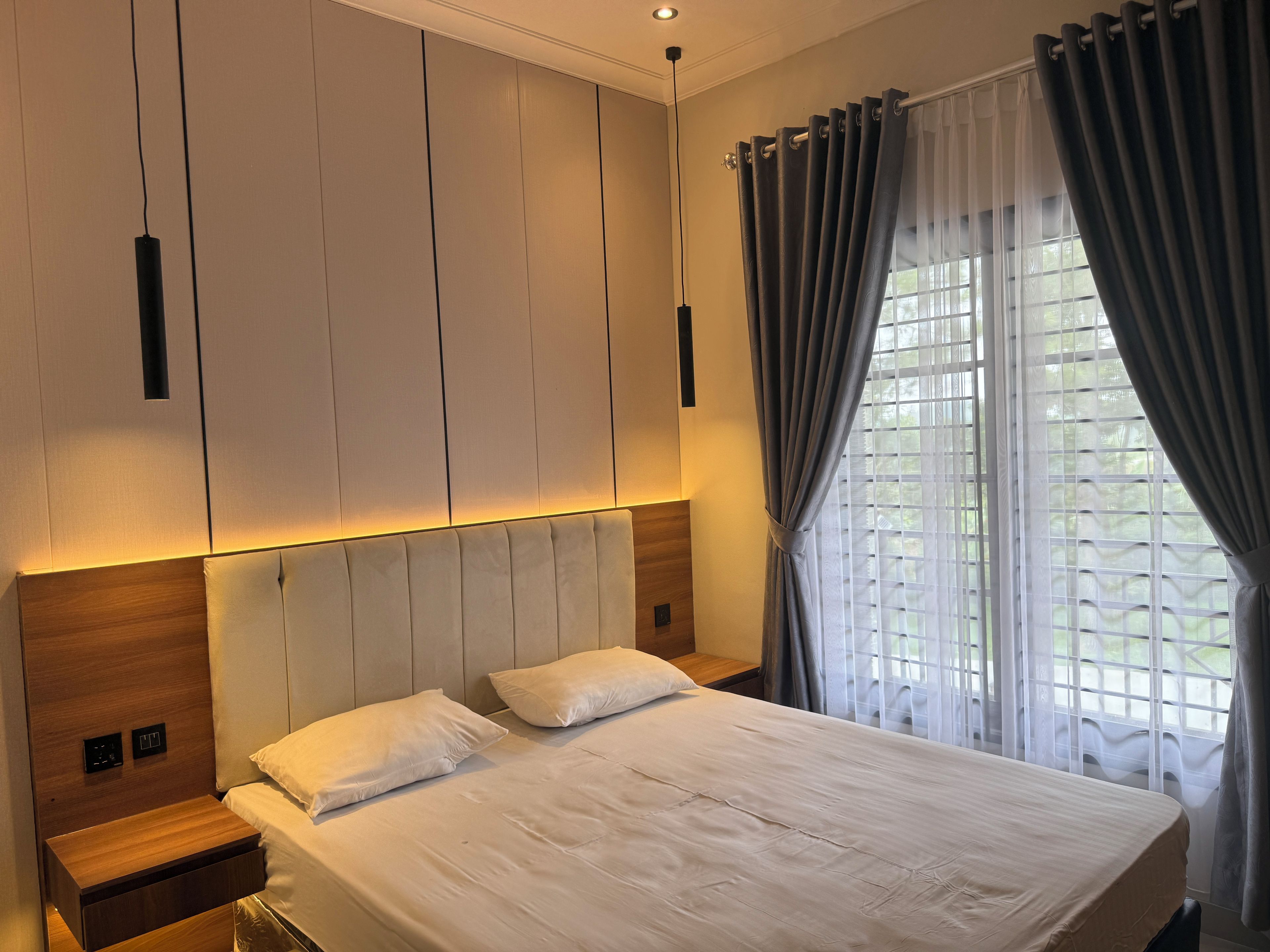 A modern bedroom with a large bed, bedside tables, and a window with curtains.