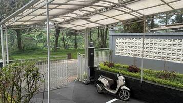 A covered outdoor area with a scooter parked, a paved walkway, and a wall with a textured pattern.