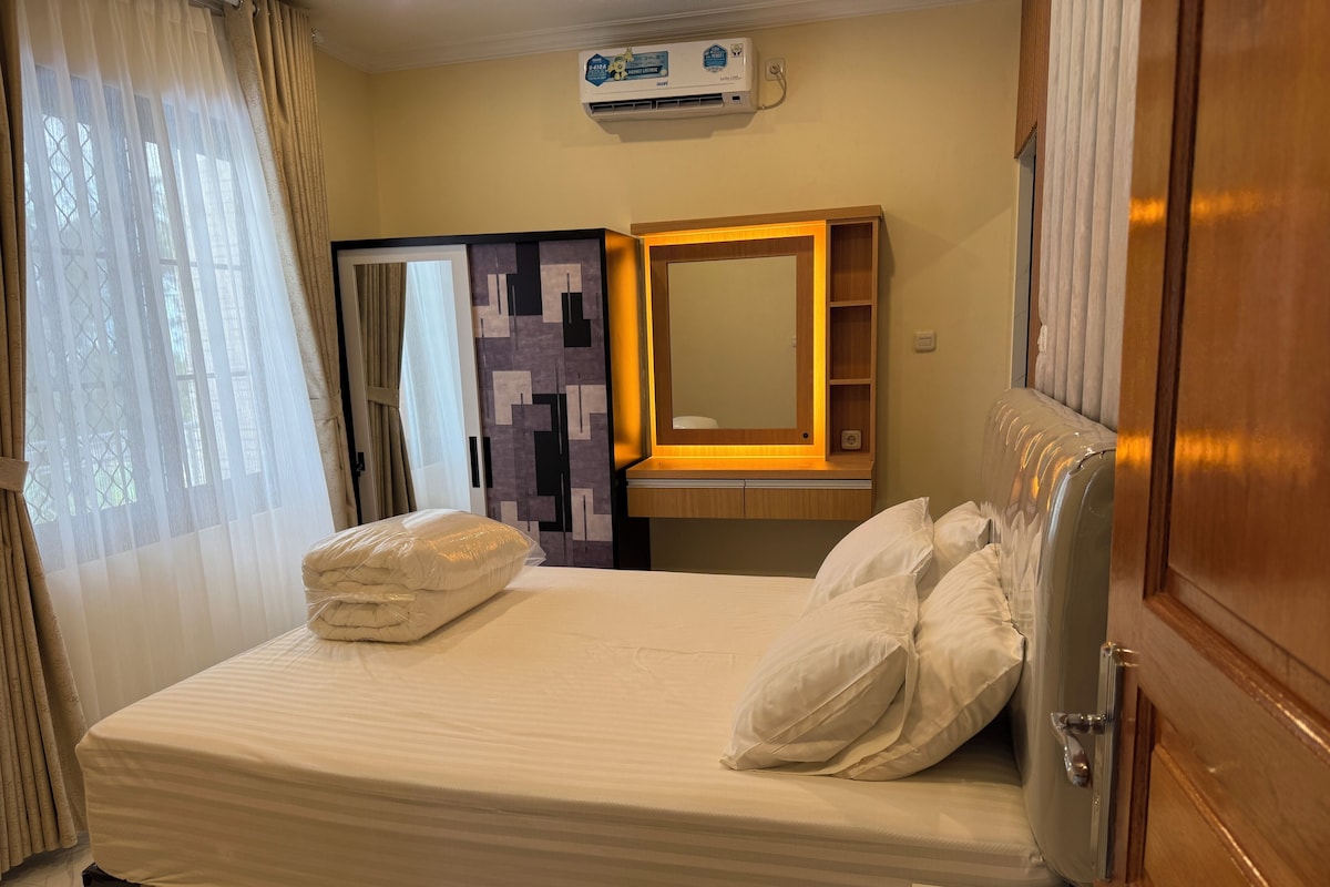 Een hotelkamer met een bed, een nachtkastje, een spiegel, een kledingkast en een airconditioning.