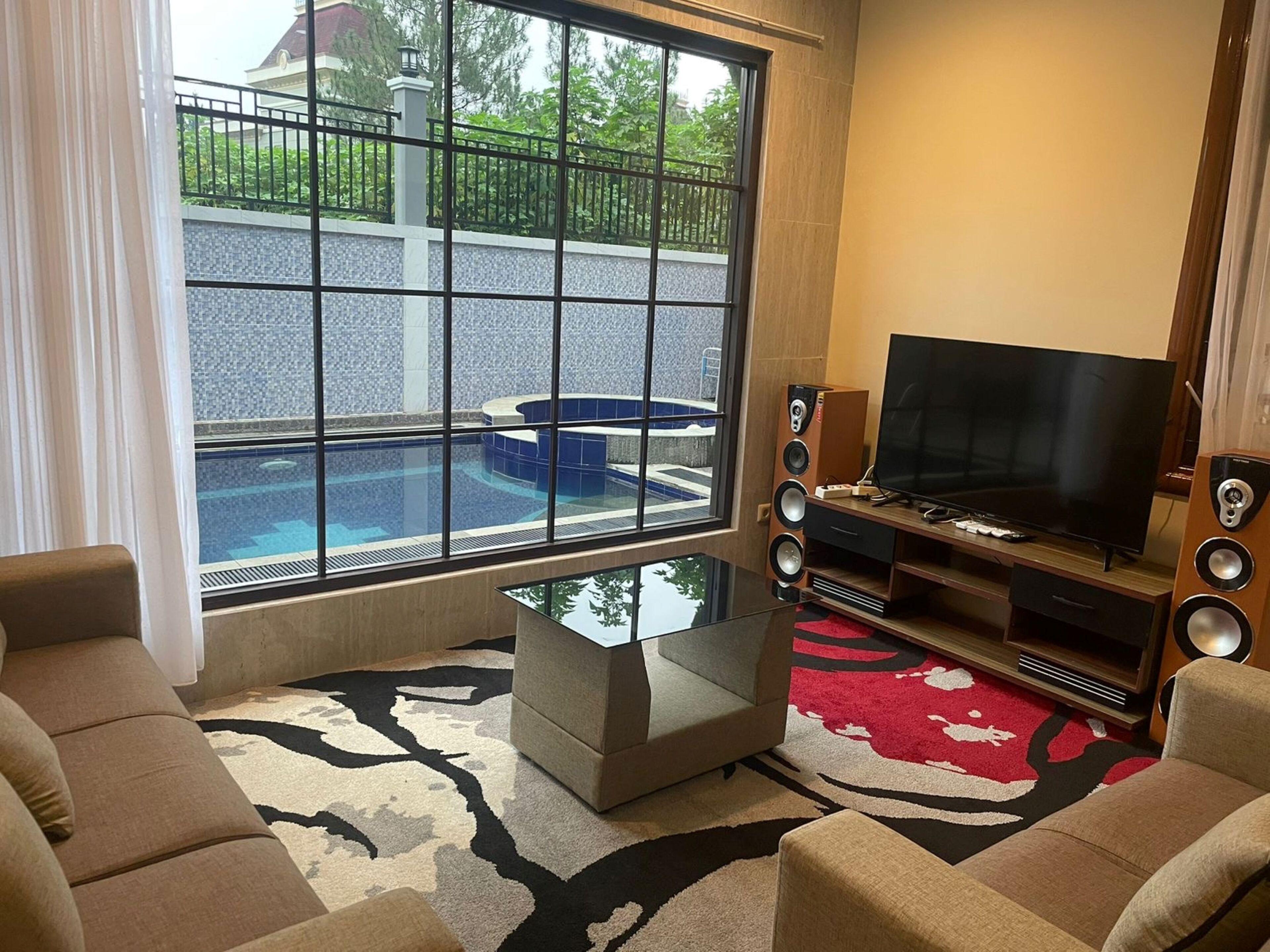 A living room with a large window, a pool, and a TV.