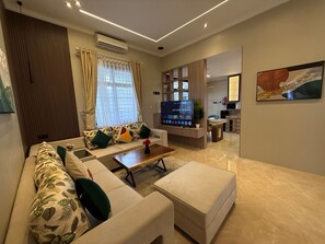 A modern living room with a sectional sofa, a coffee table, and a flat-screen TV. - Eton Asia Kota Bunga Villas (Cipanas)