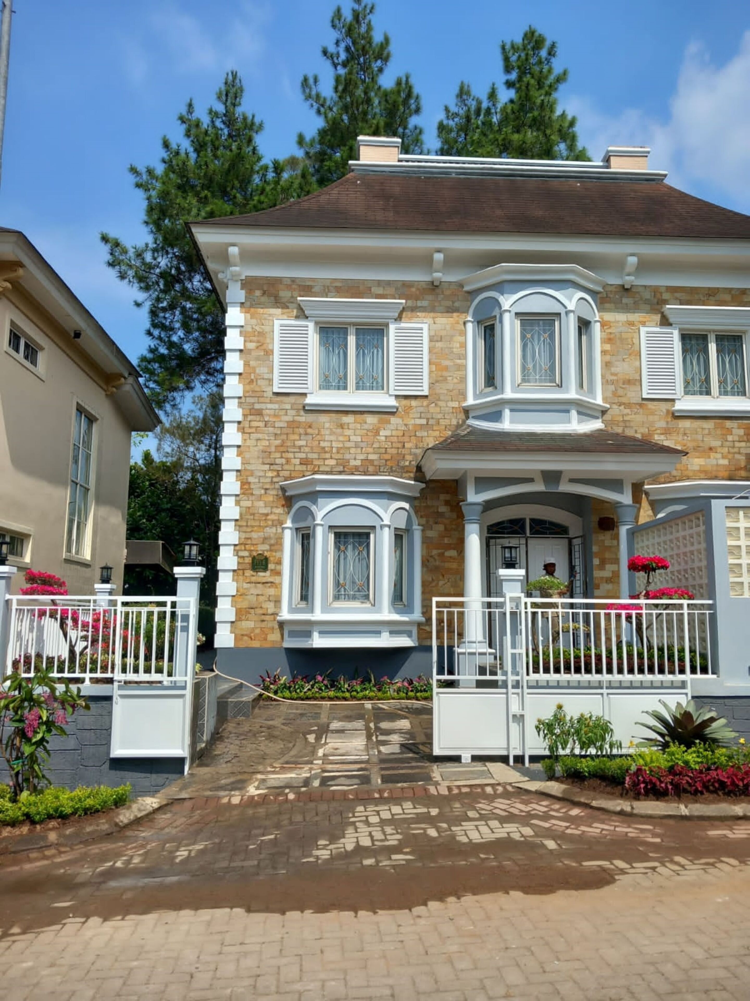 A two-story house with a brick facade, white trim, and a front porch with a white railing.