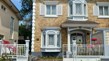 A two-story house with a brick facade, white trim, and a front porch with a white railing.