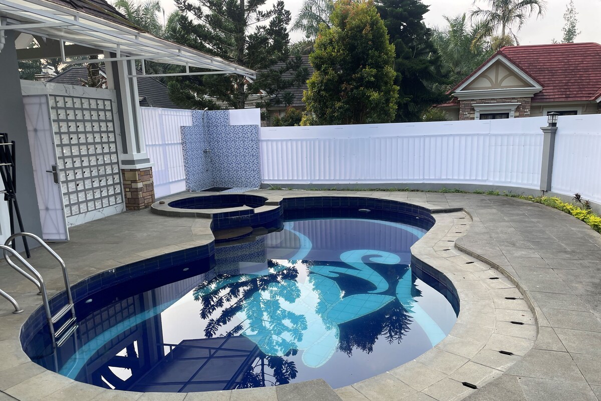 En swimmingpool med glasbund, omgivet af en terrasse med hvid hegn og et overdækket siddeområde.
