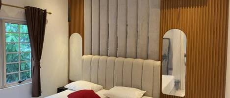 A bedroom with a large bed, a headboard, a mirror, and an air conditioning unit.