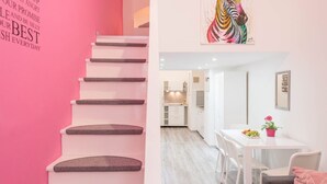 A staircase with a pink wall and a dining area with a white table and chairs. - happy home Budapest PINK   Central located apartment with 80  039 s pinball machine (Budapest)