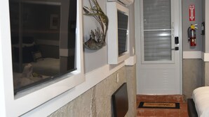 Een hotelkamer met een bed, een tafeltje, een raam, een airconditioning en een vluchtroutebord.