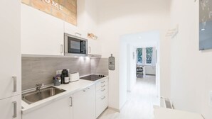 A modern kitchen with white cabinets, a stainless steel sink, a microwave, and a coffee maker. There is a sign on the wall that says "Welcome to Home." - happy home Budapest DIAMOND Central located apartment with 80 039 s pinball machine (Budapest)