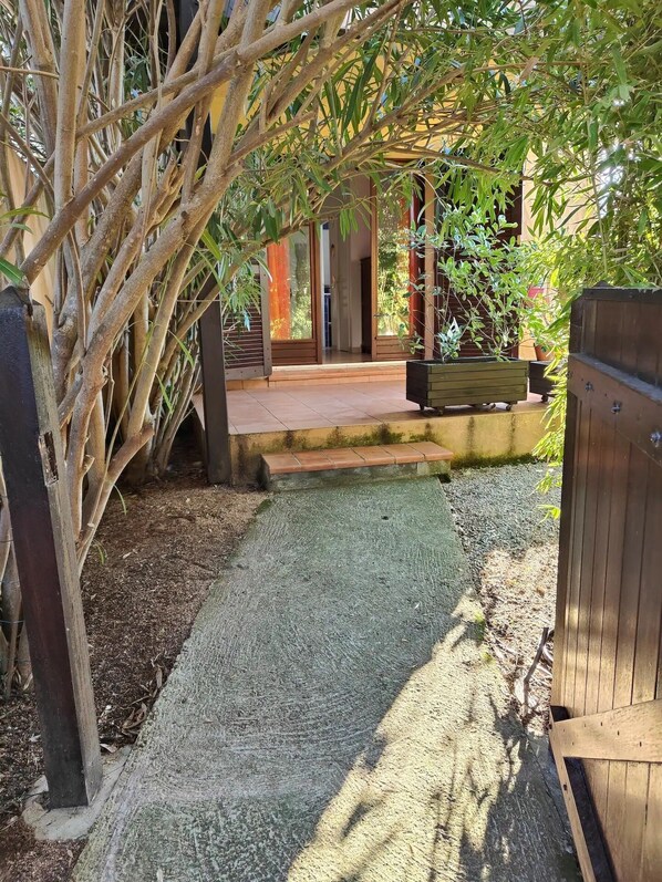 A pathway leading to a covered outdoor area with a bench and a wooden fence.