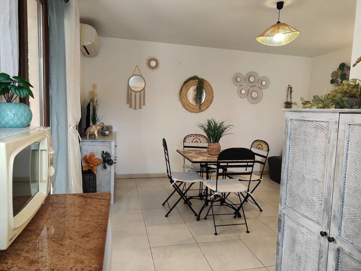 Un comedor con una mesa redonda, cuatro sillas y un espejo decorativo en la pared.