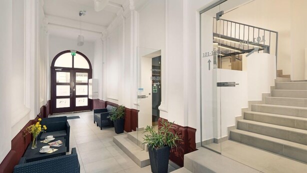 Un vestíbulo amplio con escaleras, zona de estar y mostrador de recepción.