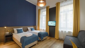 Una habitación de hotel con dos camas, televisión y sofá.